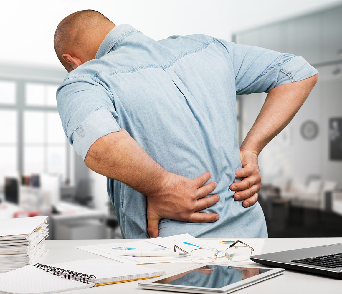 Businessman with back pain an office. Pain relief concept